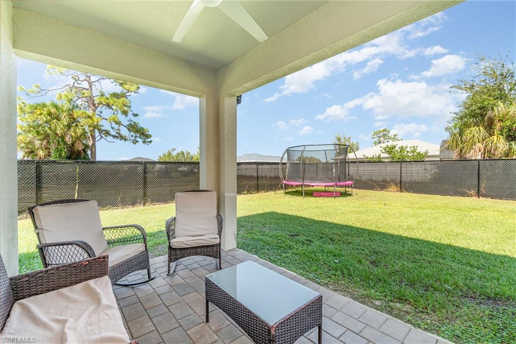 Fenced backyard featuring a patio area, a trampoline, and a ceiling fan