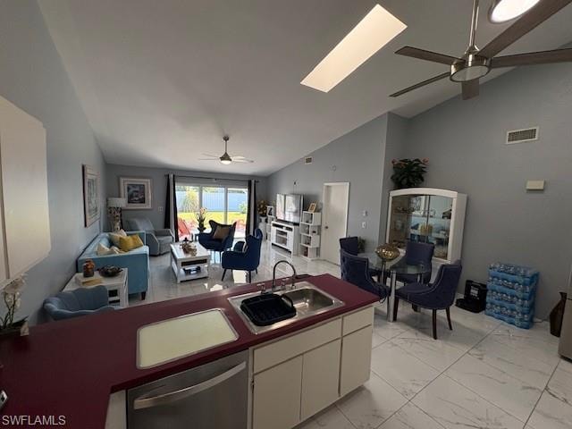 Kitchen featuring a ceiling fan, lofted ceiling, white cabinetry, open floor plan, and stainless steel dishwasher