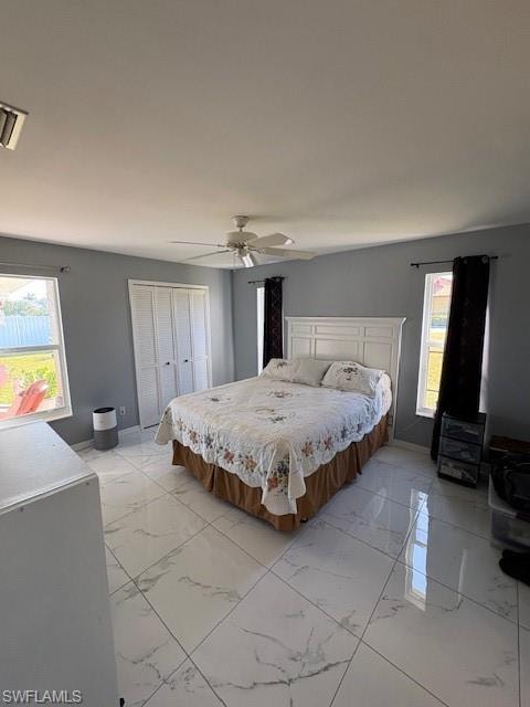 Bedroom featuring light marble finish flooring, a closet, and a ceiling fan