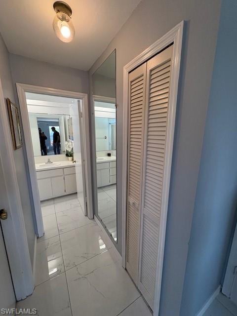 Hall with light marble finish flooring and a sink