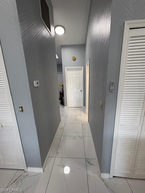 Hall with light marble finish flooring and a textured wall