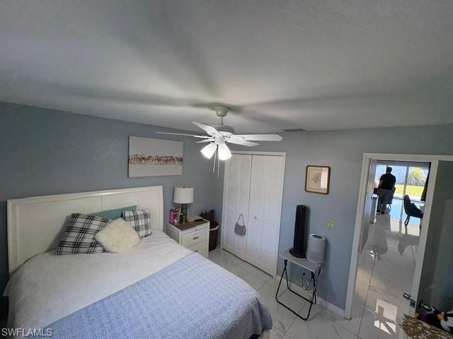 Bedroom with a ceiling fan, a closet, and light marble finish flooring