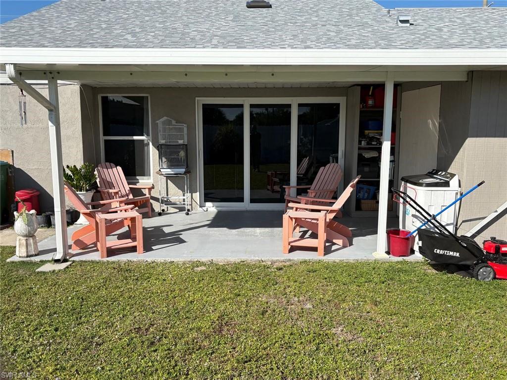 Back of house featuring roof with shingles, a patio area, and a lawn