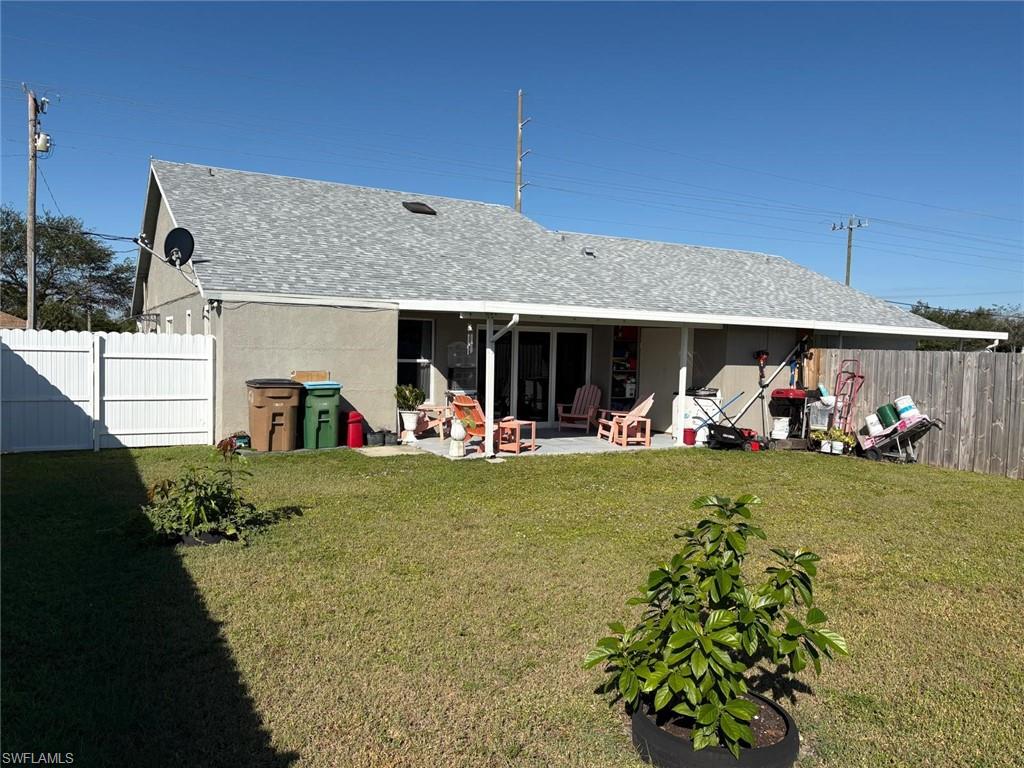 Rear view of property featuring a patio area, a fenced backyard, roof with shingles, and stucco siding