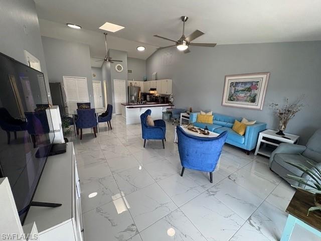 Living room featuring vaulted ceiling, light marble finish floors, and a ceiling fan