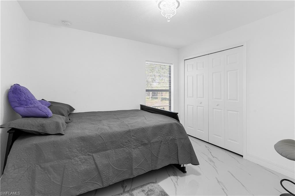 Bedroom with light marble finish floors and a closet