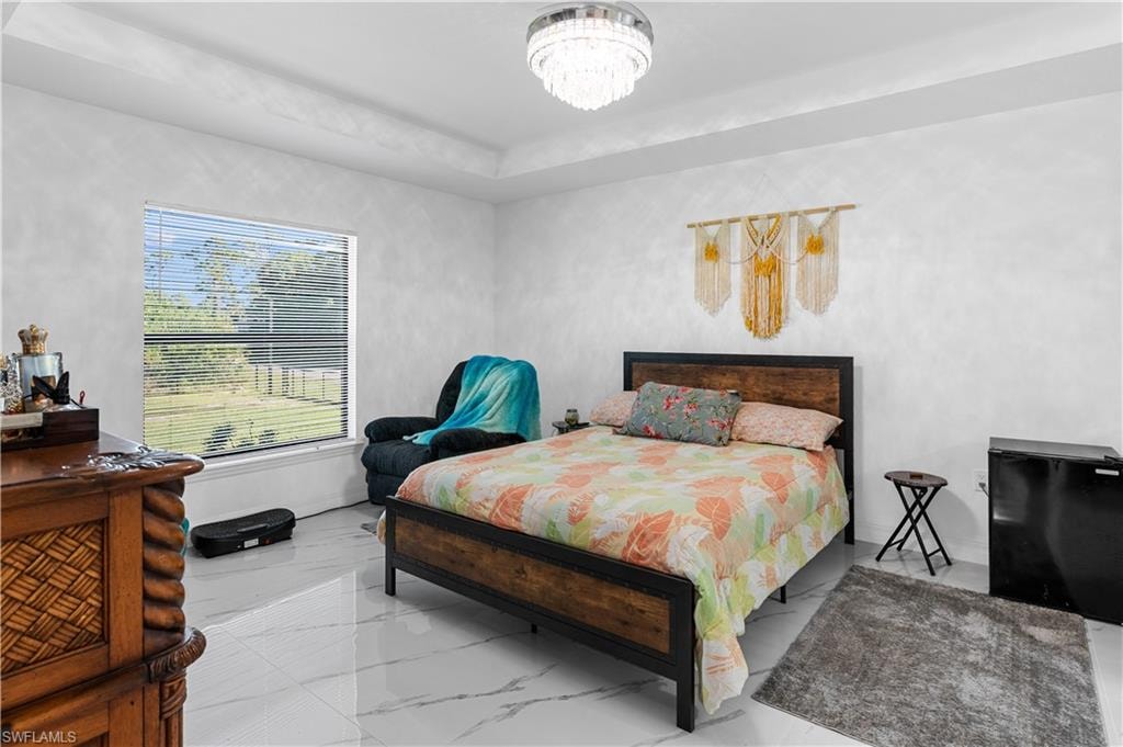 Bedroom featuring marble look tile flooring and a chandelier