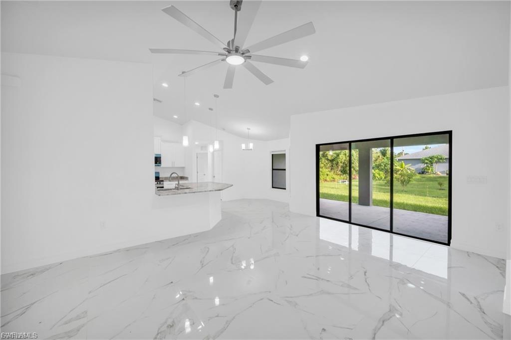 Unfurnished living room featuring lofted ceiling, light marble finish floors, and recessed lighting