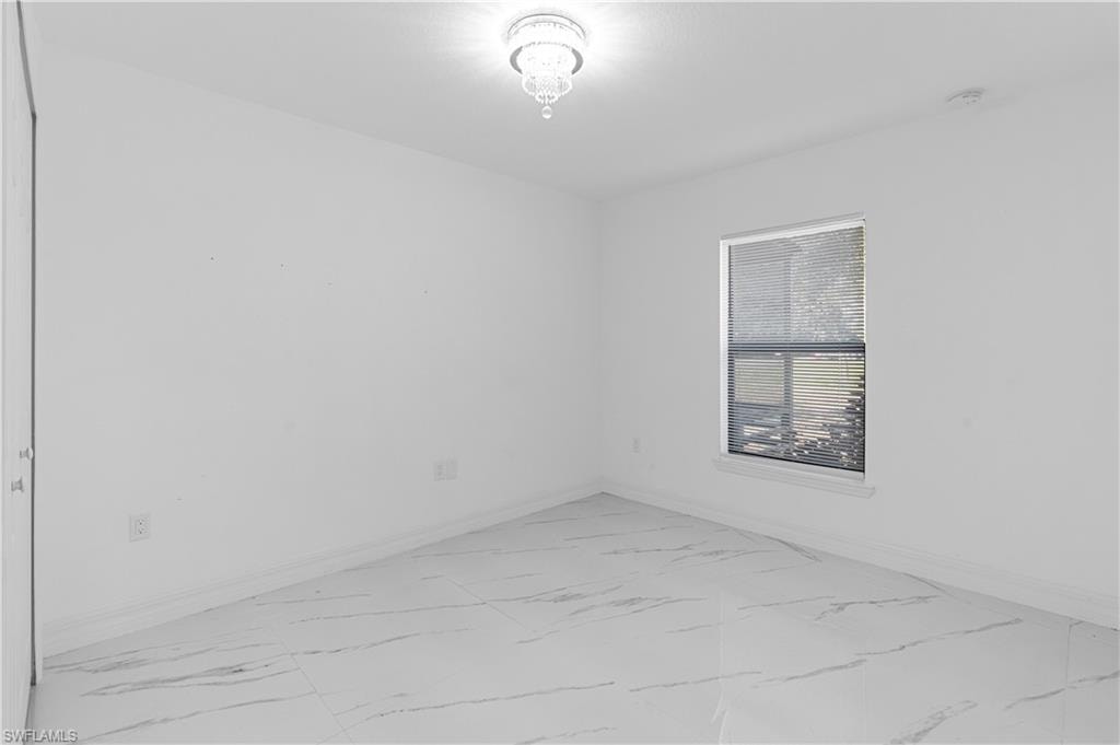 Empty room featuring light marble finish flooring and baseboards