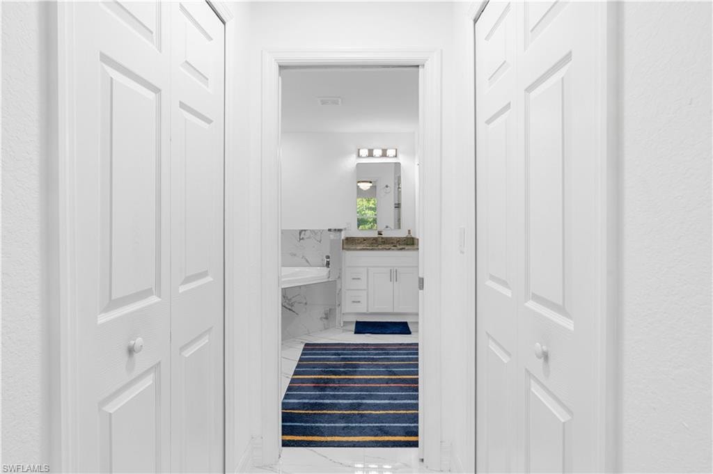 Full bathroom with a closet, vanity, a bath, and marble look tiles