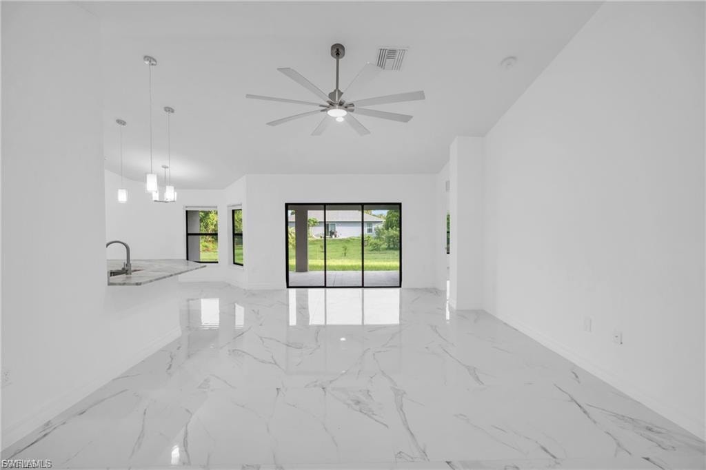Spare room with light marble finish floors and ceiling fan