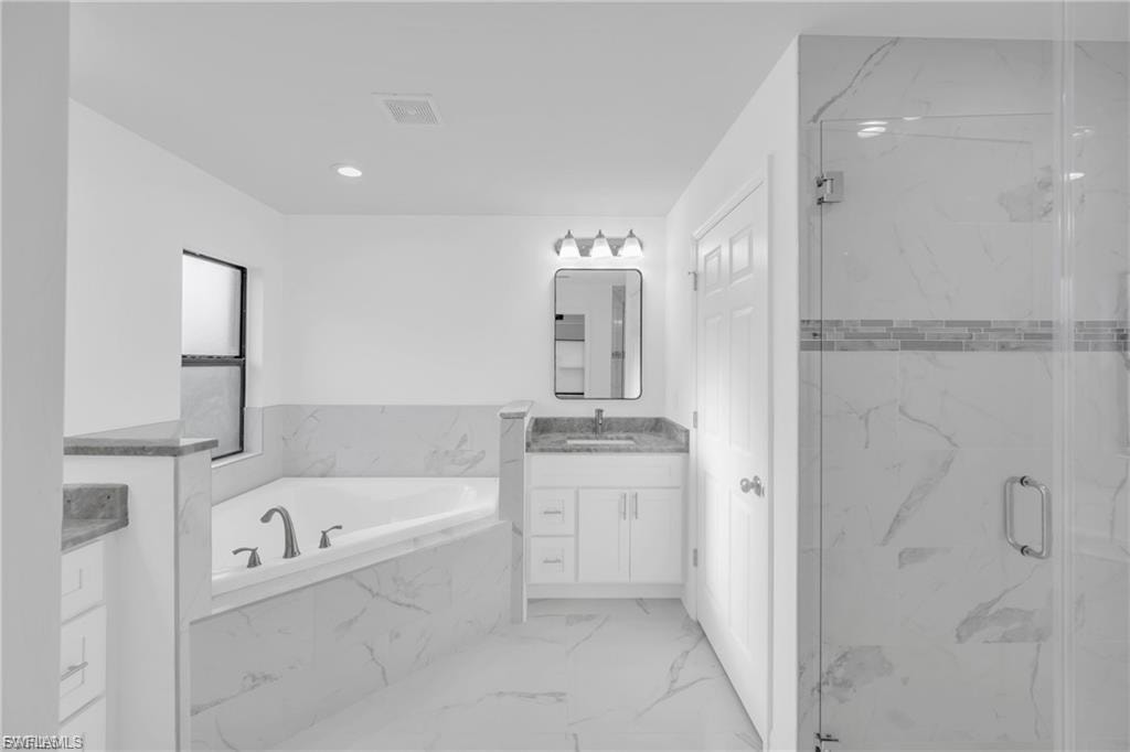 Full bathroom featuring a bath, vanity, light marble finish flooring, and a marble finish shower