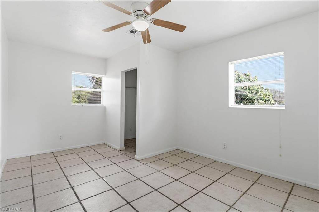 Unfurnished bedroom with light tile patterned flooring, multiple windows, and a ceiling fan