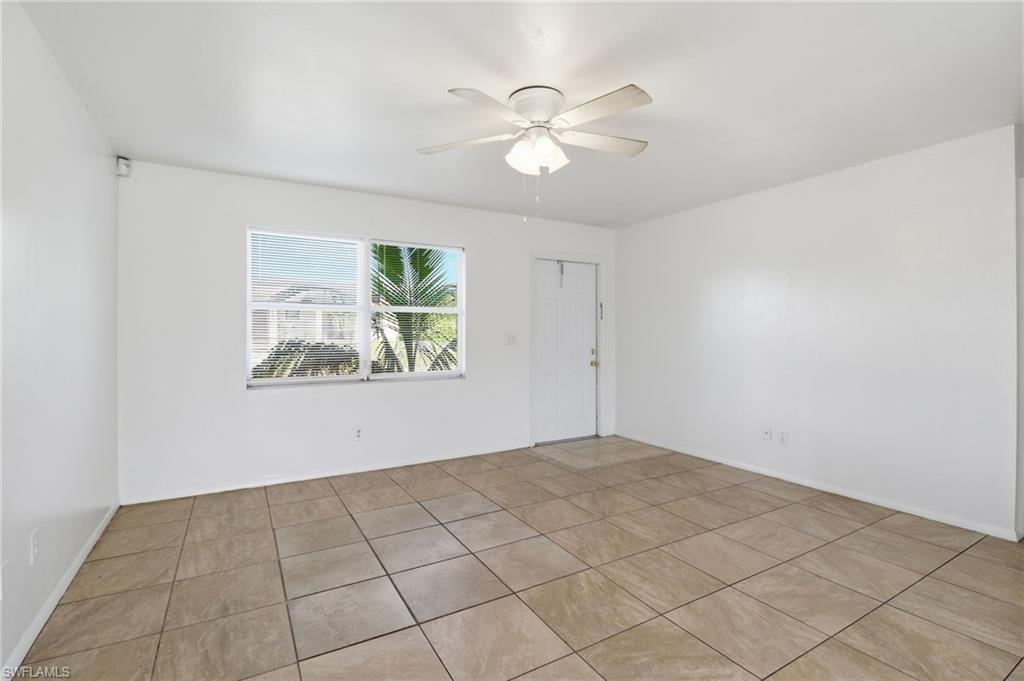 Tiled empty room featuring baseboards and a ceiling fan