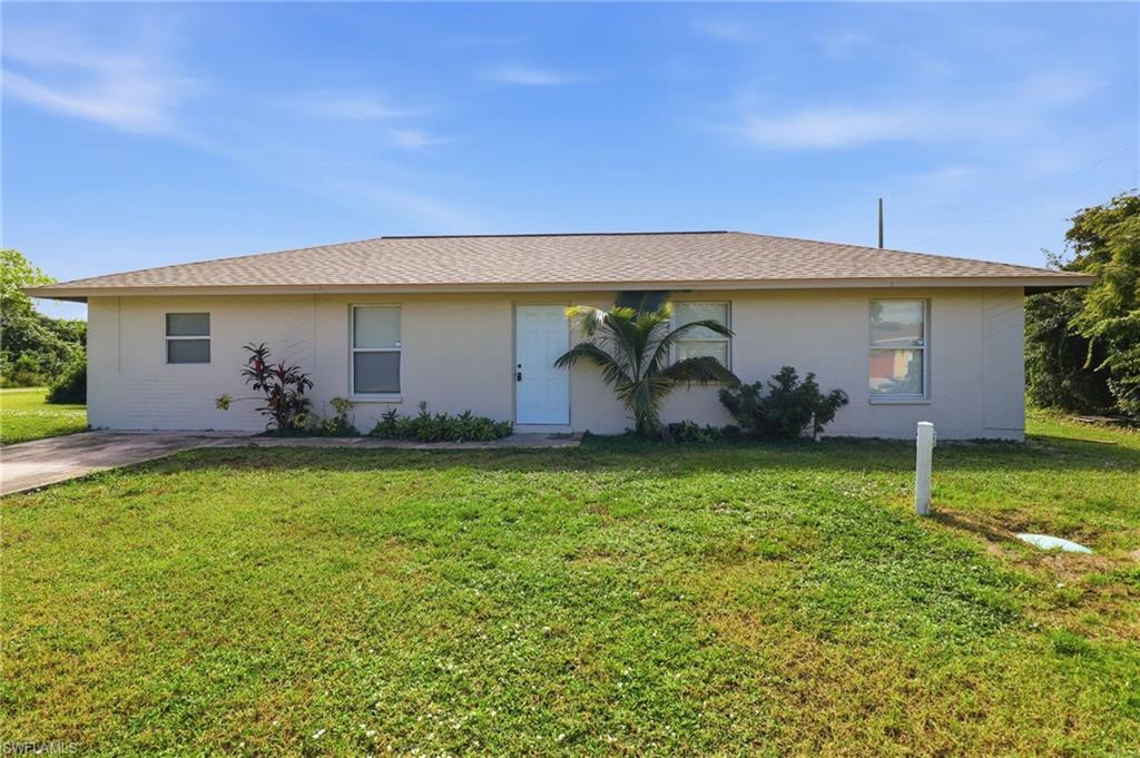 Single story home with a front lawn, a shingled roof, and stucco siding