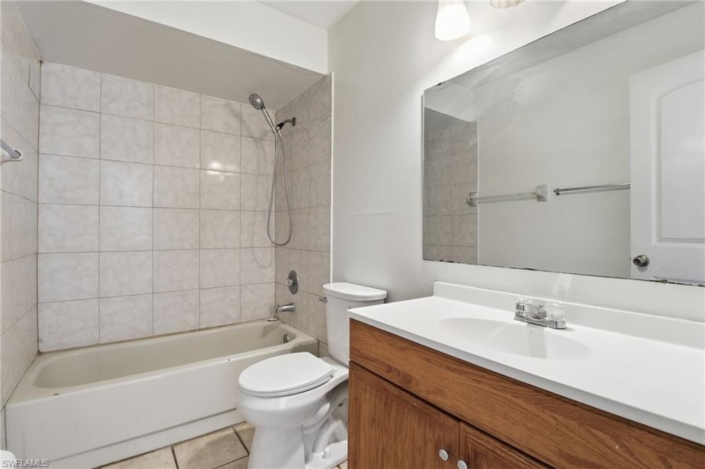 Full bathroom with shower / bath combination, vanity, and light tile patterned floors