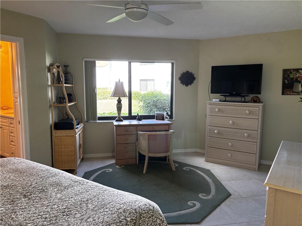 Bedroom with ceiling fan, light tile patterned floors, and ensuite bathroom