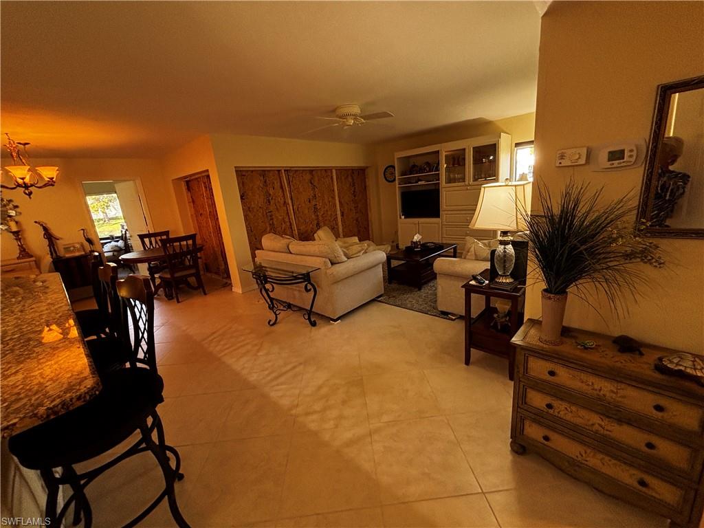 Living area featuring a ceiling fan, a chandelier, and light tile patterned floors