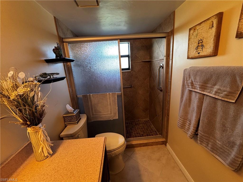 Bathroom with light tile patterned floors, a stall shower, and vanity