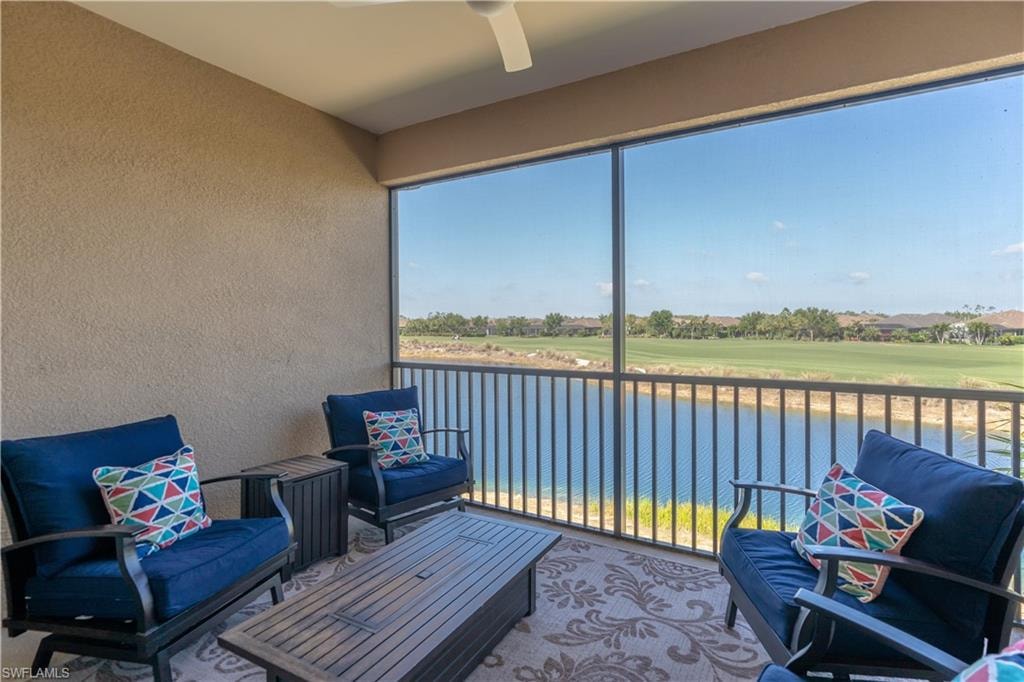 Sunroom with a balcony, a water view, ceiling fan, and golf course view