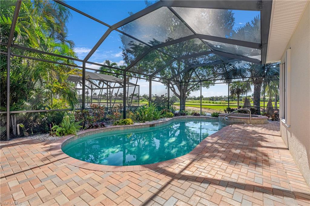 View of swimming pool with a sunroom, glass enclosure, a patio, and a pool with connected hot tub