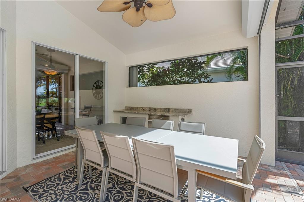 Sunroom with outdoor dining space, a patio area, a ceiling fan, vaulted ceiling, and an outdoor kitchen