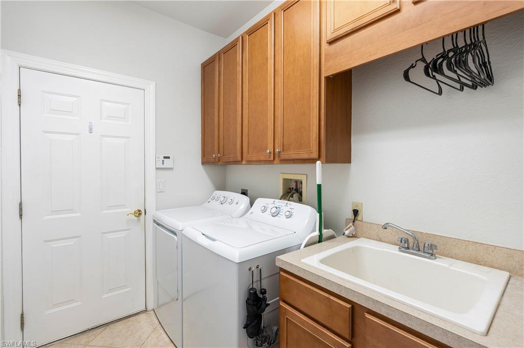 Laundry area featuring cabinet space, light tile patterned floors, and washer and dryer
