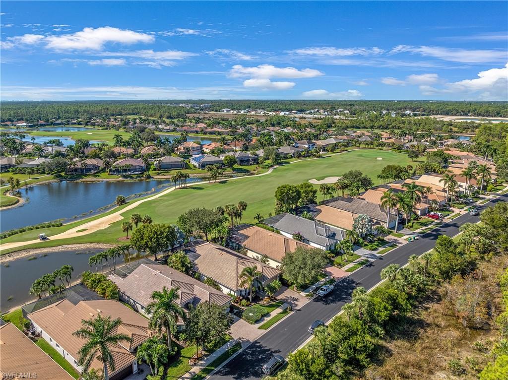 Aerial view of property and surrounding area featuring nearby suburban area, a local golf course, and a nearby body of water