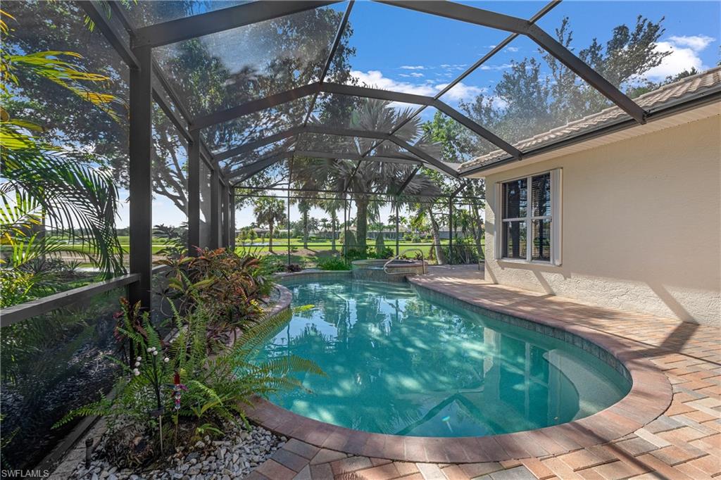 View of pool with a sunroom, a patio area, glass enclosure, and a pool with connected hot tub