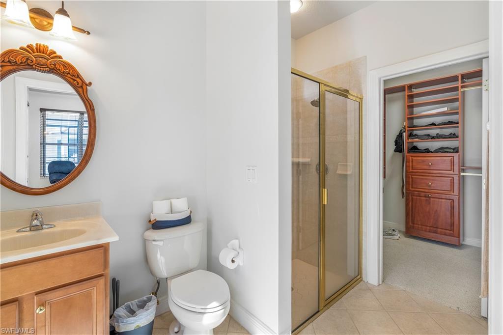 Full bathroom with a shower stall, light tile patterned floors, vanity, and a spacious closet