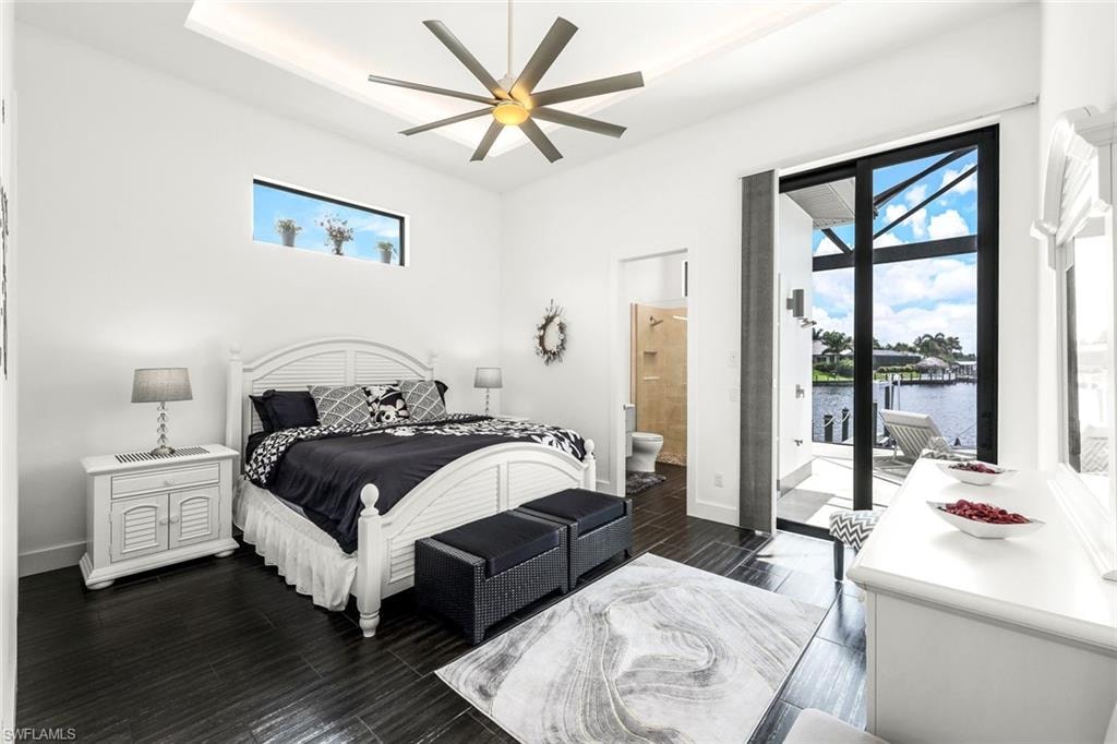 Bedroom featuring dark wood-type flooring, access to exterior, ceiling fan, and a water view