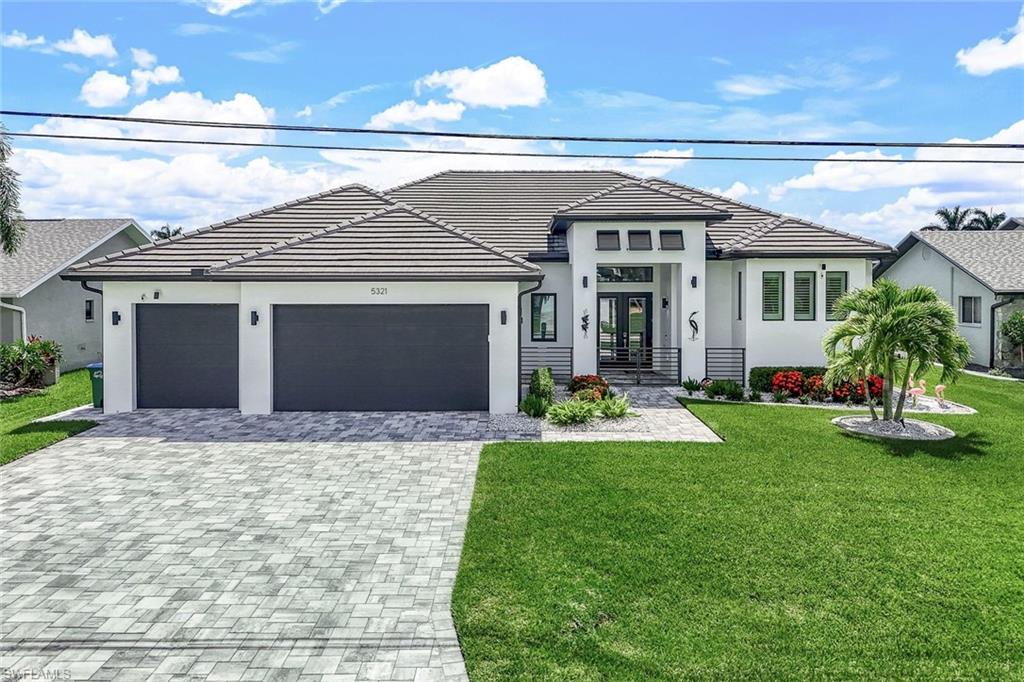 View of front of house with a front yard, stucco siding, and decorative driveway