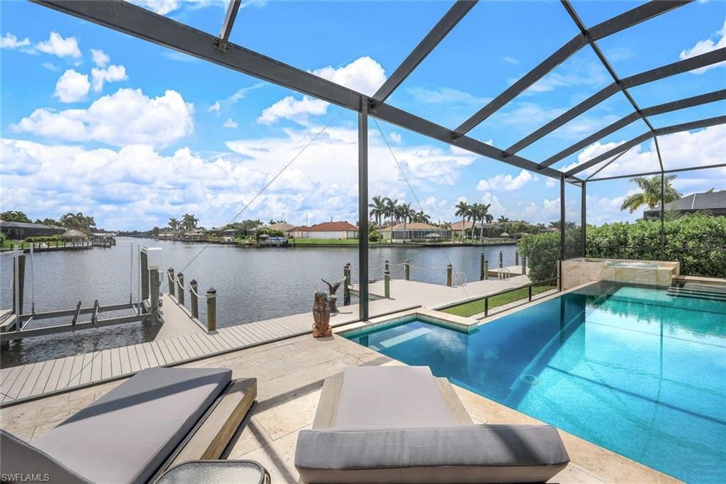 View of swimming pool featuring boat lift, a dock, a water view, a sunroom, and a pool with connected hot tub