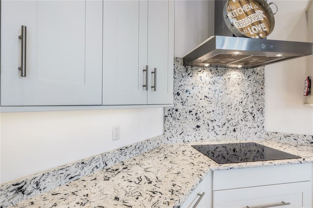 Kitchen featuring range hood, tasteful backsplash, and white cabinetry