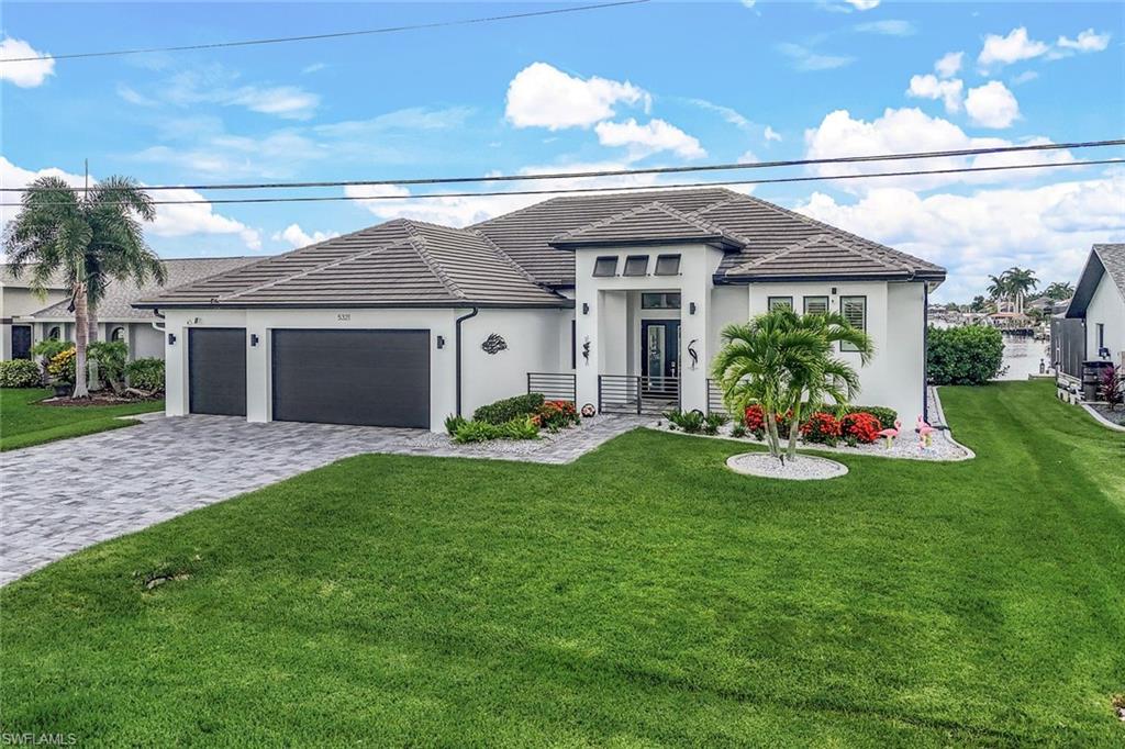 View of front facade with a front lawn, decorative driveway, a garage, stucco siding, and a tiled roof