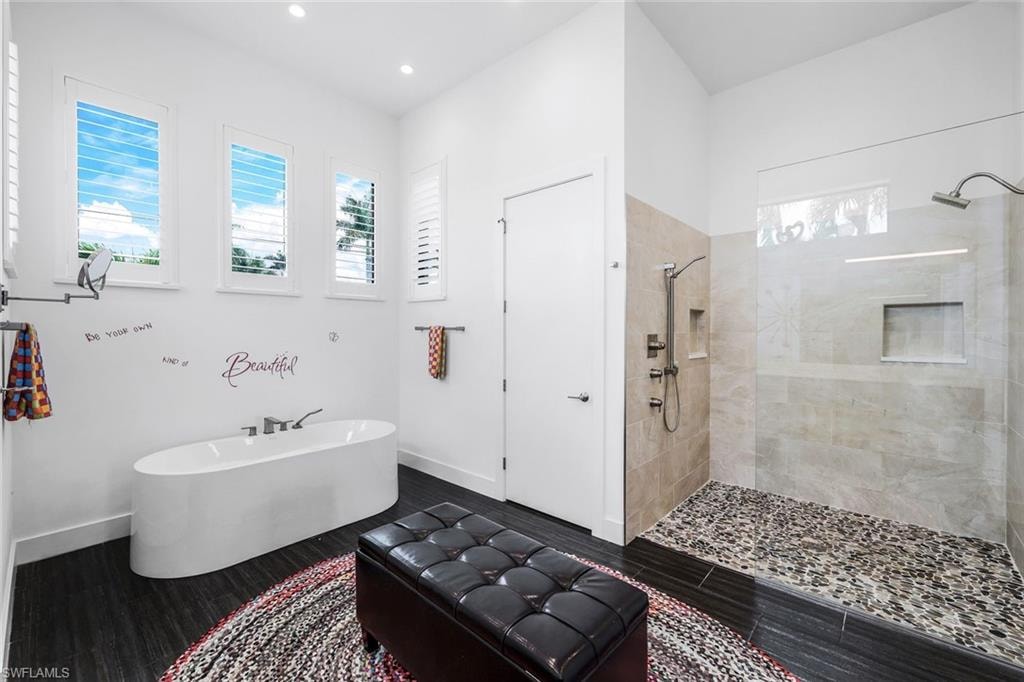 Full bathroom featuring a walk in shower, a freestanding bath, wood finished floors, and recessed lighting