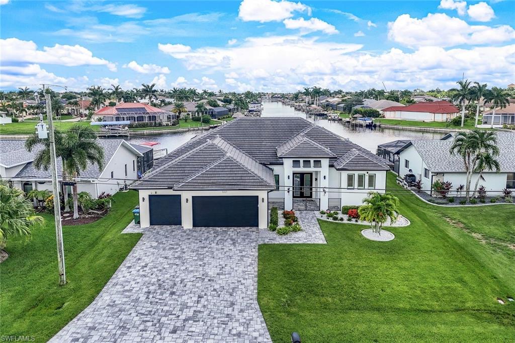 View of front of property with a water view, a residential view, a front yard, and decorative driveway