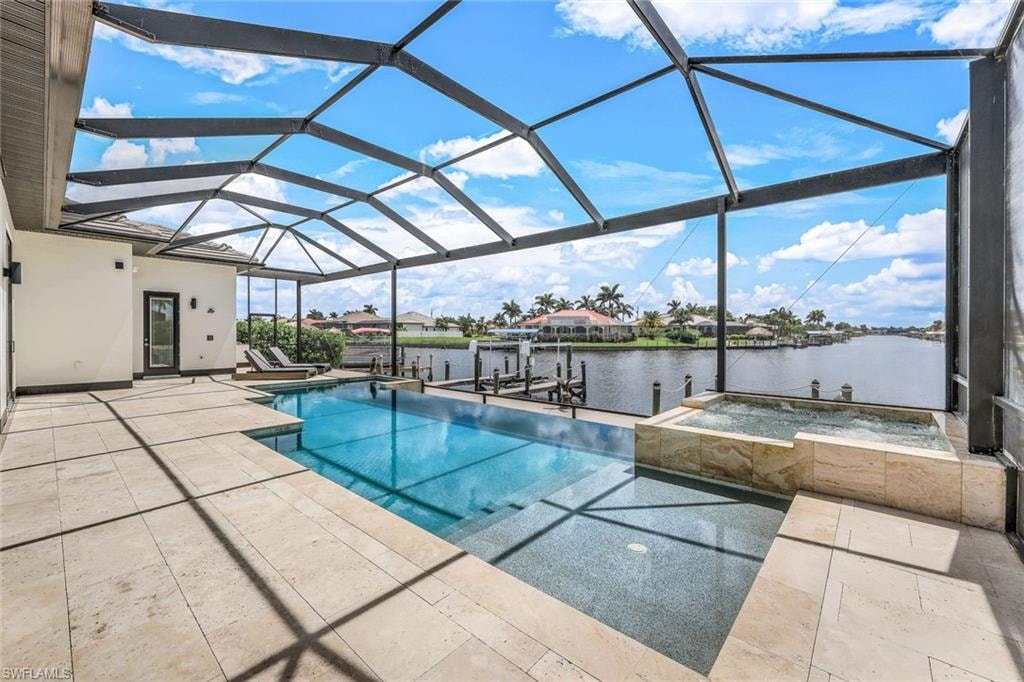 View of pool with a sunroom, boat lift, a patio area, a water view, and a boat dock