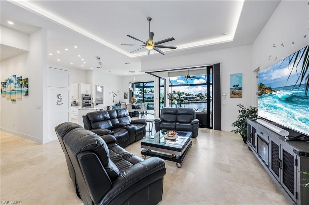 Living area with a raised ceiling, a ceiling fan, and recessed lighting