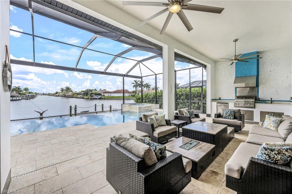 View of pool featuring a sunroom, an outdoor hangout area, a water view, an outdoor kitchen, and a patio area