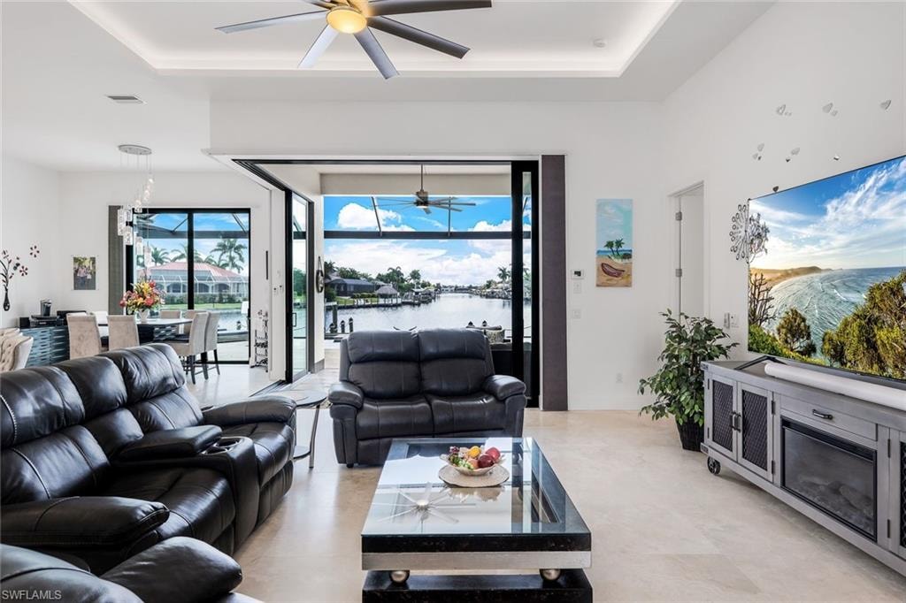 Living area with a raised ceiling, a chandelier, and ceiling fan