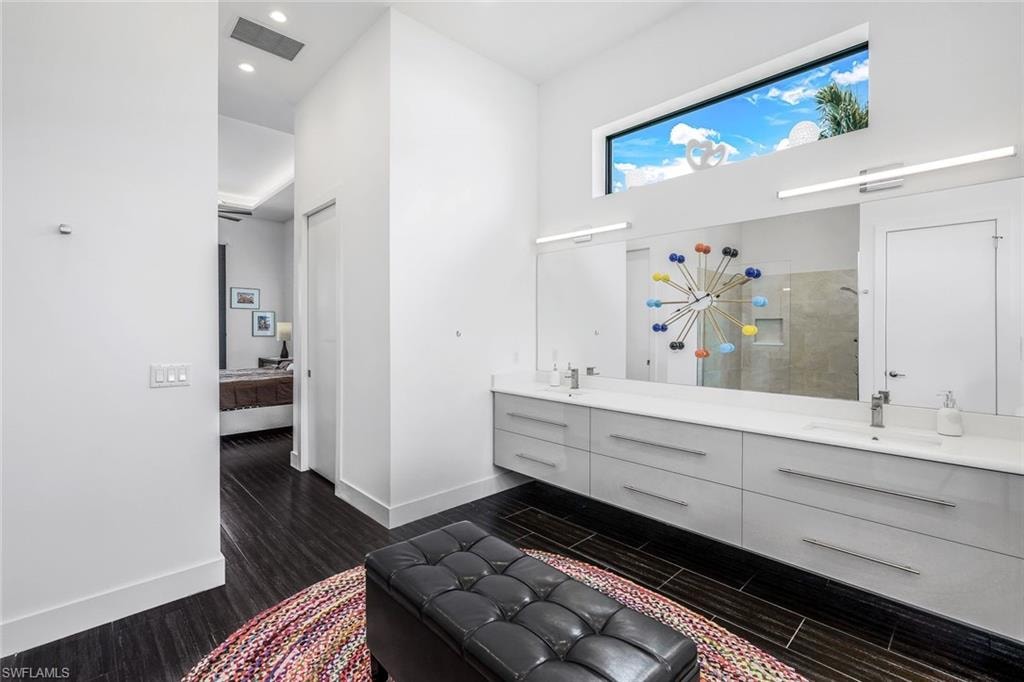 Ensuite bathroom featuring dark wood-type flooring, a shower stall, double vanity, and recessed lighting