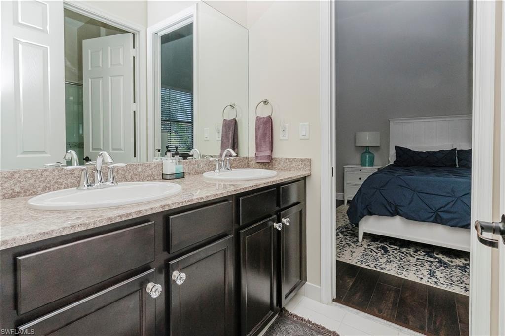 Ensuite bathroom with double vanity and light wood-type flooring