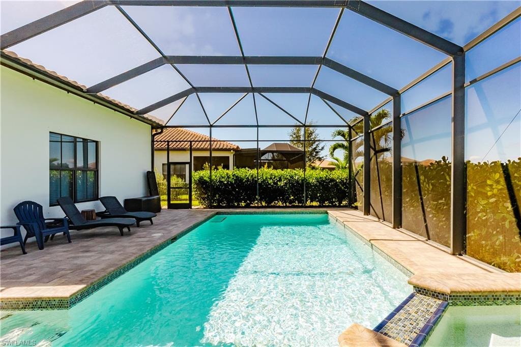 Swimming pool featuring a patio area, a lanai, and a sunroom