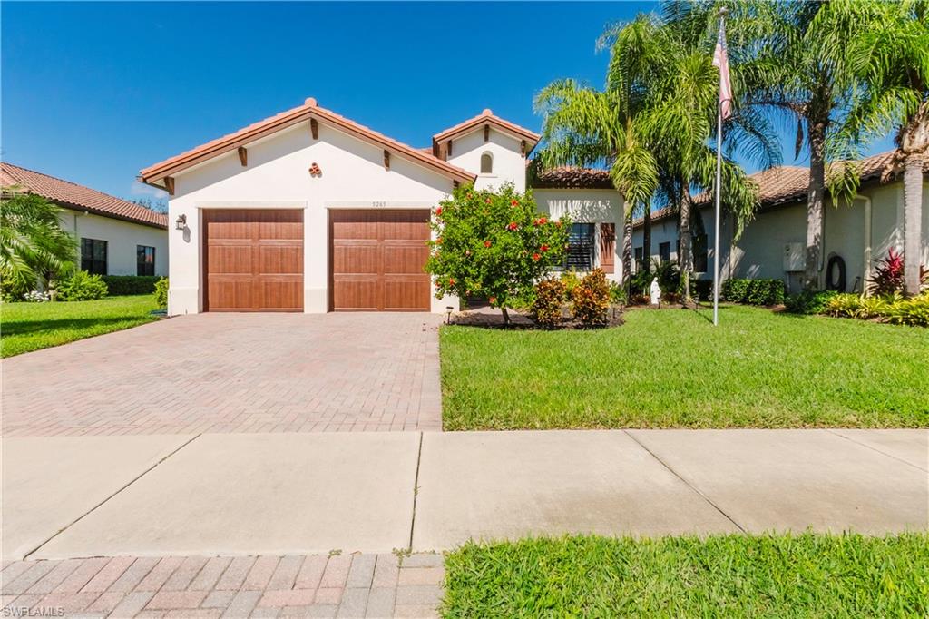 Mediterranean / spanish-style home featuring a front yard, stucco siding, decorative driveway, and an attached garage