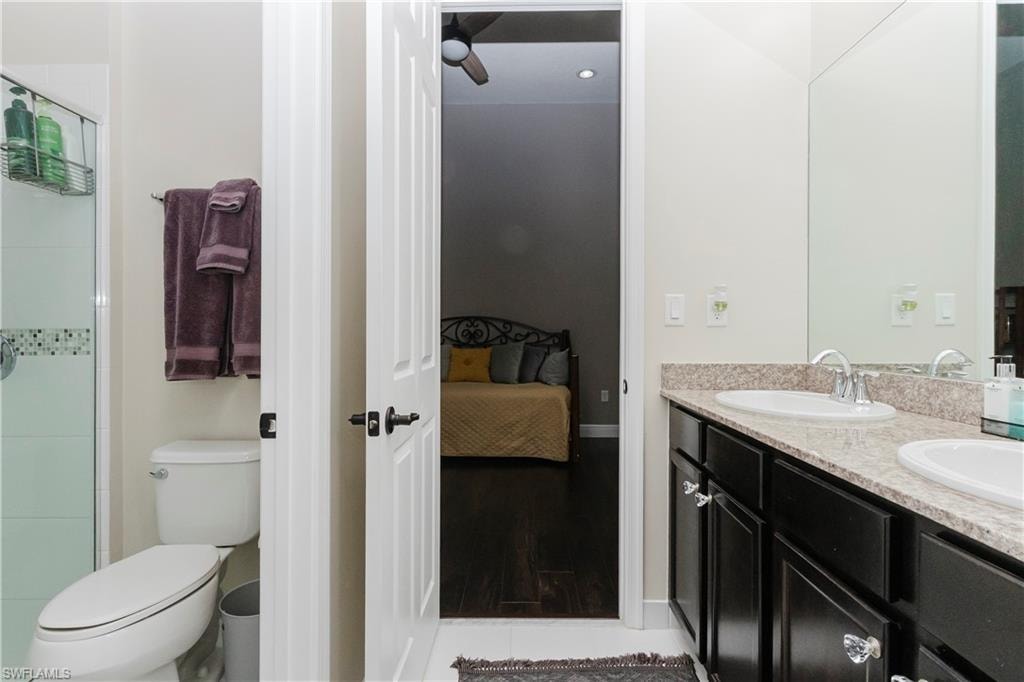 Full bathroom featuring ensuite bathroom, double vanity, a stall shower, and light wood finished floors