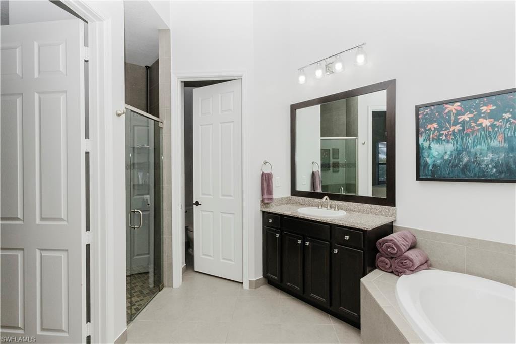 Full bath with vanity, a bath, a shower stall, and light tile patterned floors
