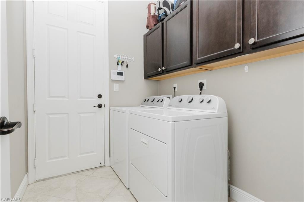 Washroom with washing machine and clothes dryer, cabinet space, and light tile patterned floors