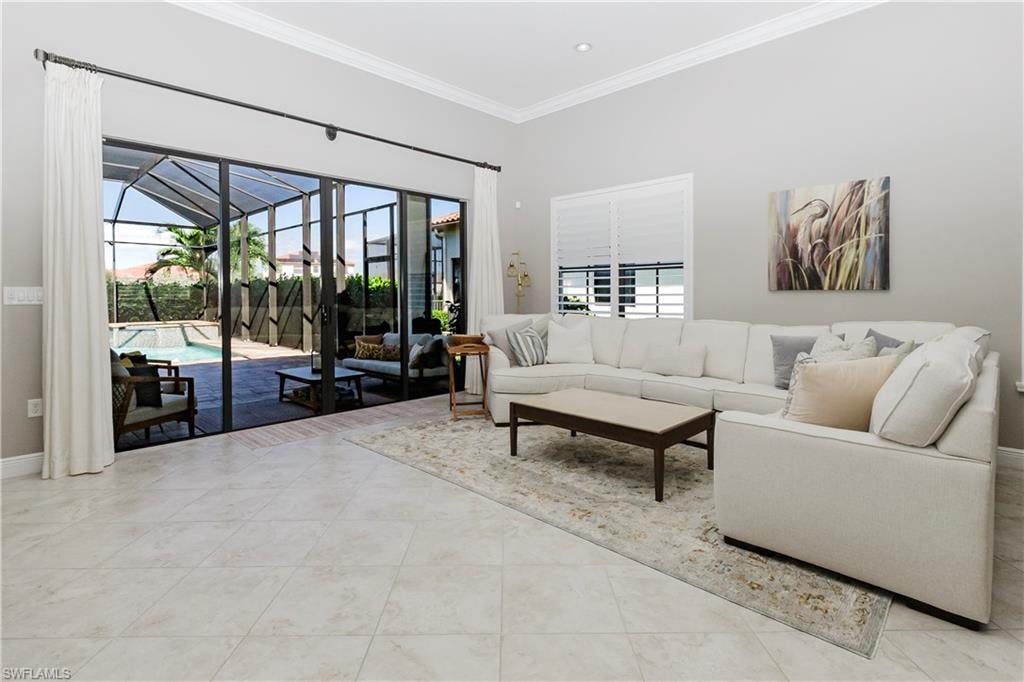 Living room with a sunroom, healthy amount of natural light, ornamental molding, and light tile patterned flooring