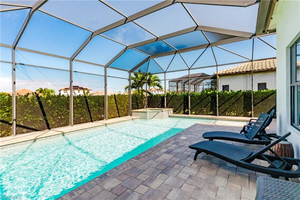 View of swimming pool with a sunroom, a lanai, a pool with connected hot tub, and a patio area